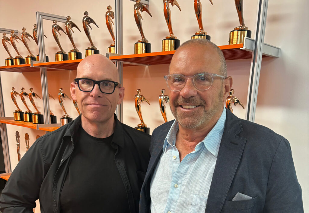 Image of Rick Chiorando and Bryan Hynes standing in front of shelves filled with awards